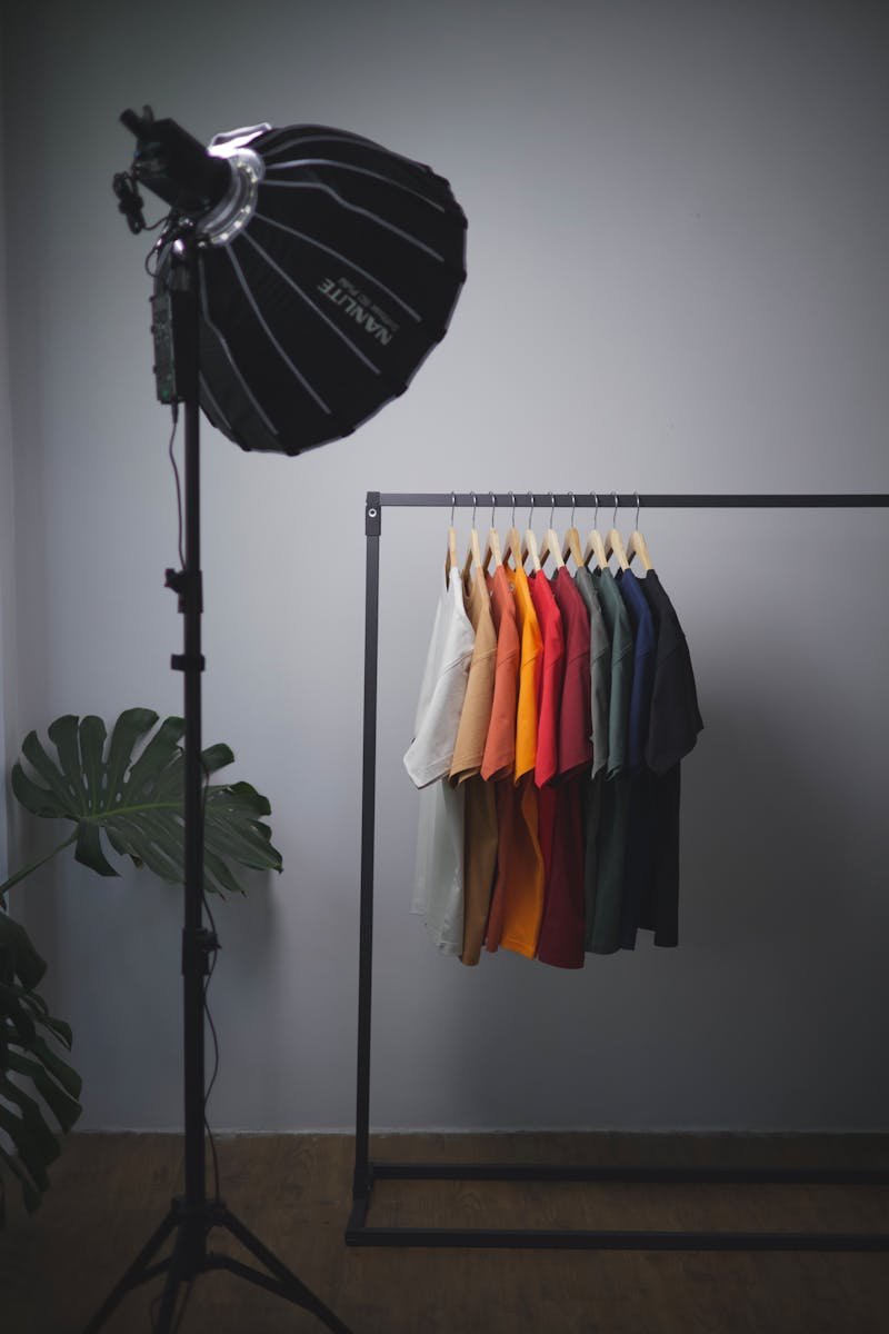 Colorful shirts on rack under studio light, showcasing minimalist style.